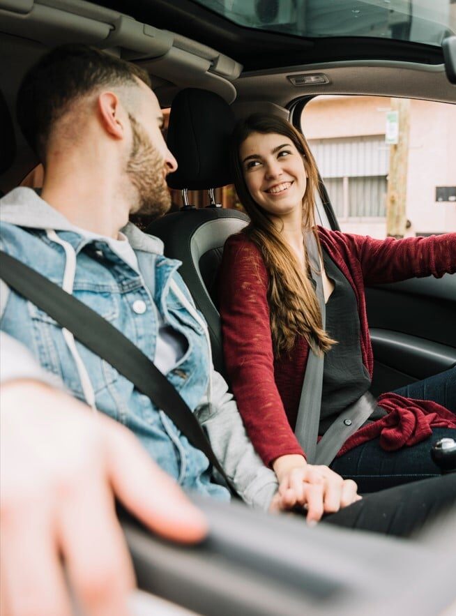 Ein Paar lächelt sich in einem Mietwagen von 57MOBIL an.