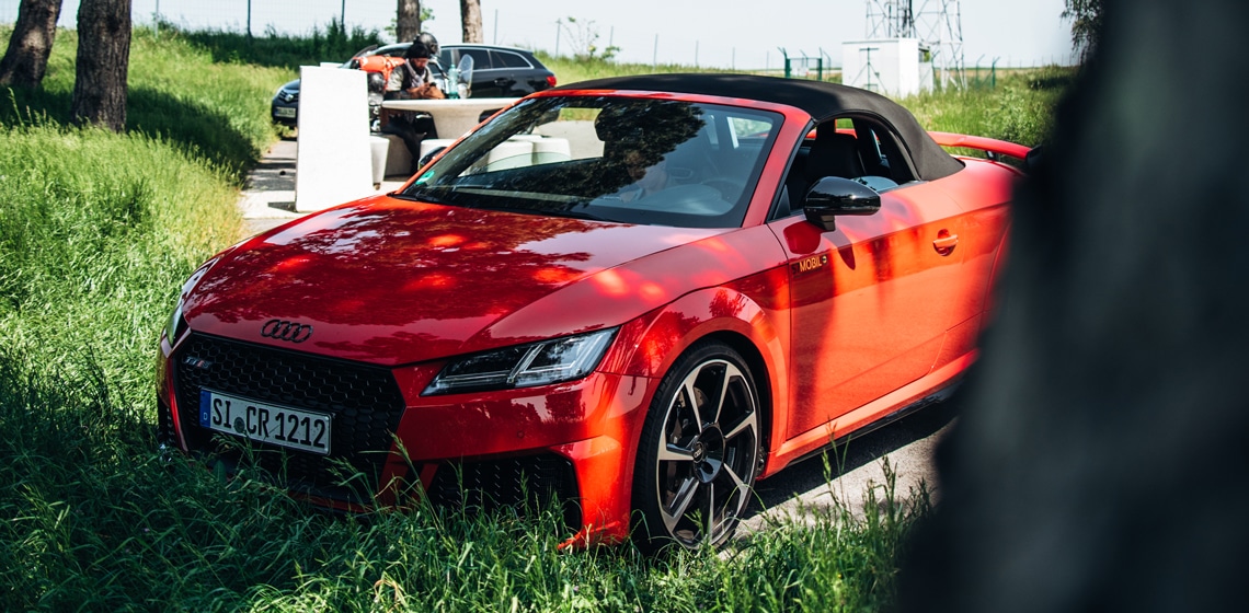 Ein roter Audi Sportwagen, auf einem Parkplatz positioniert für leistungsstarke Abenteuerfahrten zum Mieten.