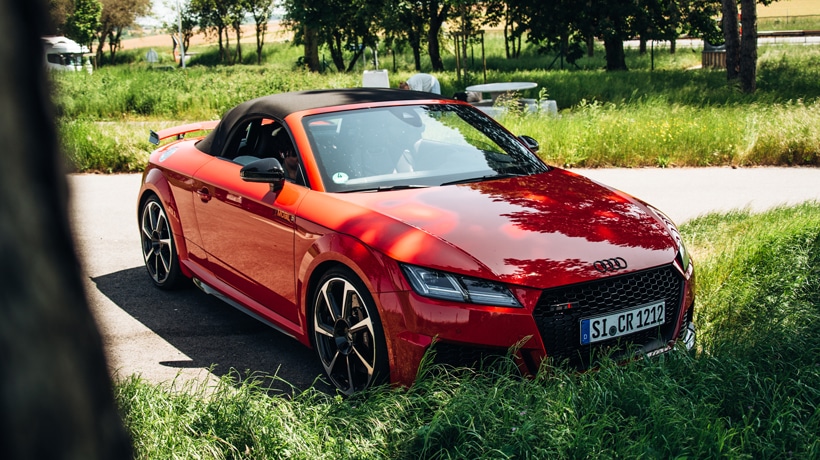 Roter Sportwagen auf einem Rastplatz - perfekte Wahl für eine Abenteuerfahrt zum Mieten.