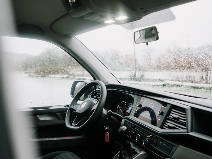 Aufnahme des Fahrzeuginnenraums eines VW Transporters, der über 57Mobil zum Mieten zur Verfügung steht. Durch die Fenster sieht man, dass es draußen regnet.