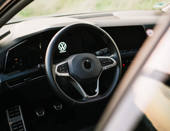 Blick durch geöffnetes Fahrzeugfenster auf das Lenkrad eines VW Golf 8 | Auto Abo