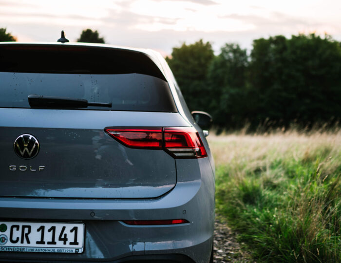 Angeschnittene Heckansicht eines auf einem Feldweg abgestellten VW Golf 8 | Auto Abo